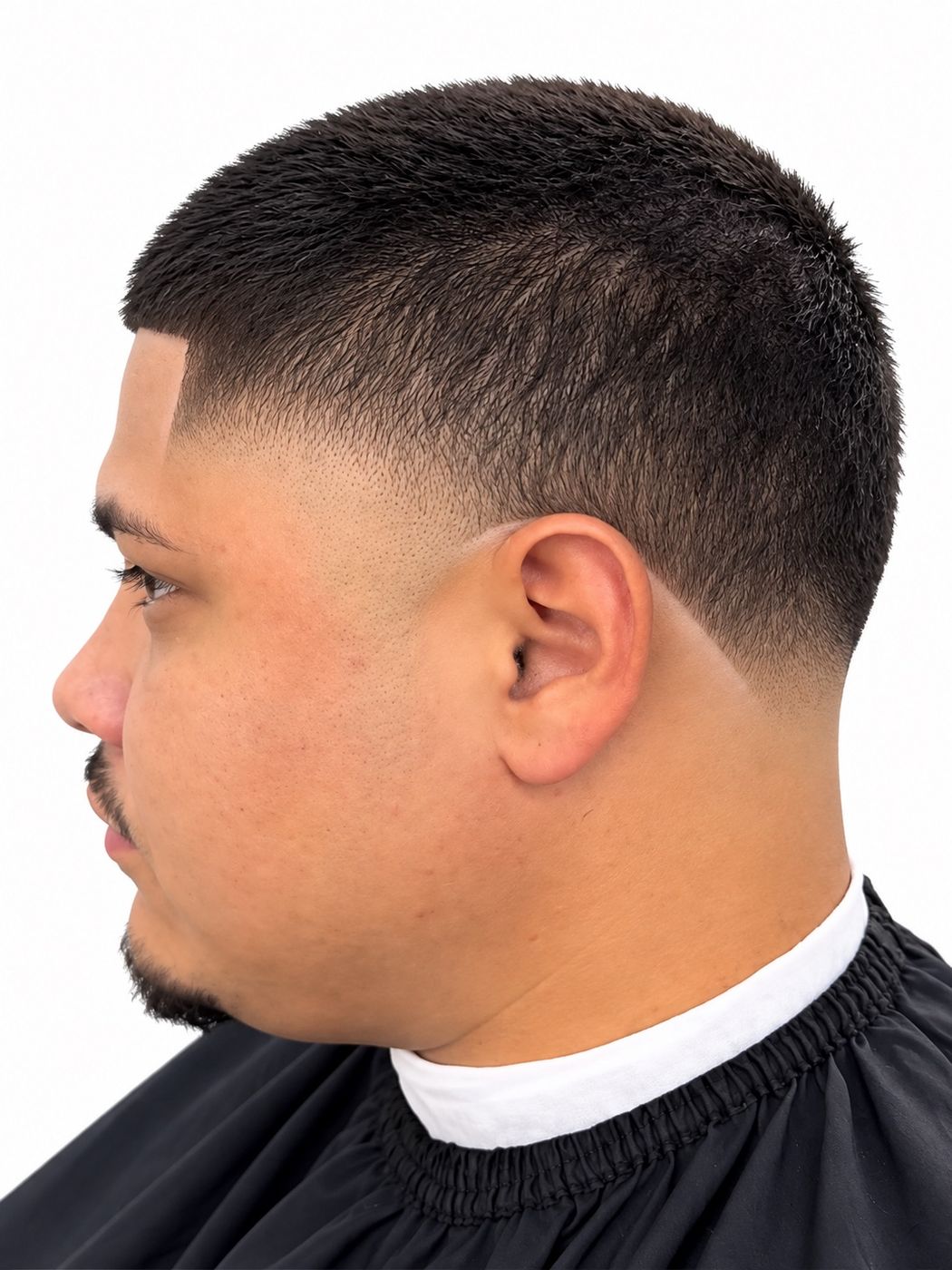 High drop fade on a short crop with a sharp line-up and goatee, left profile